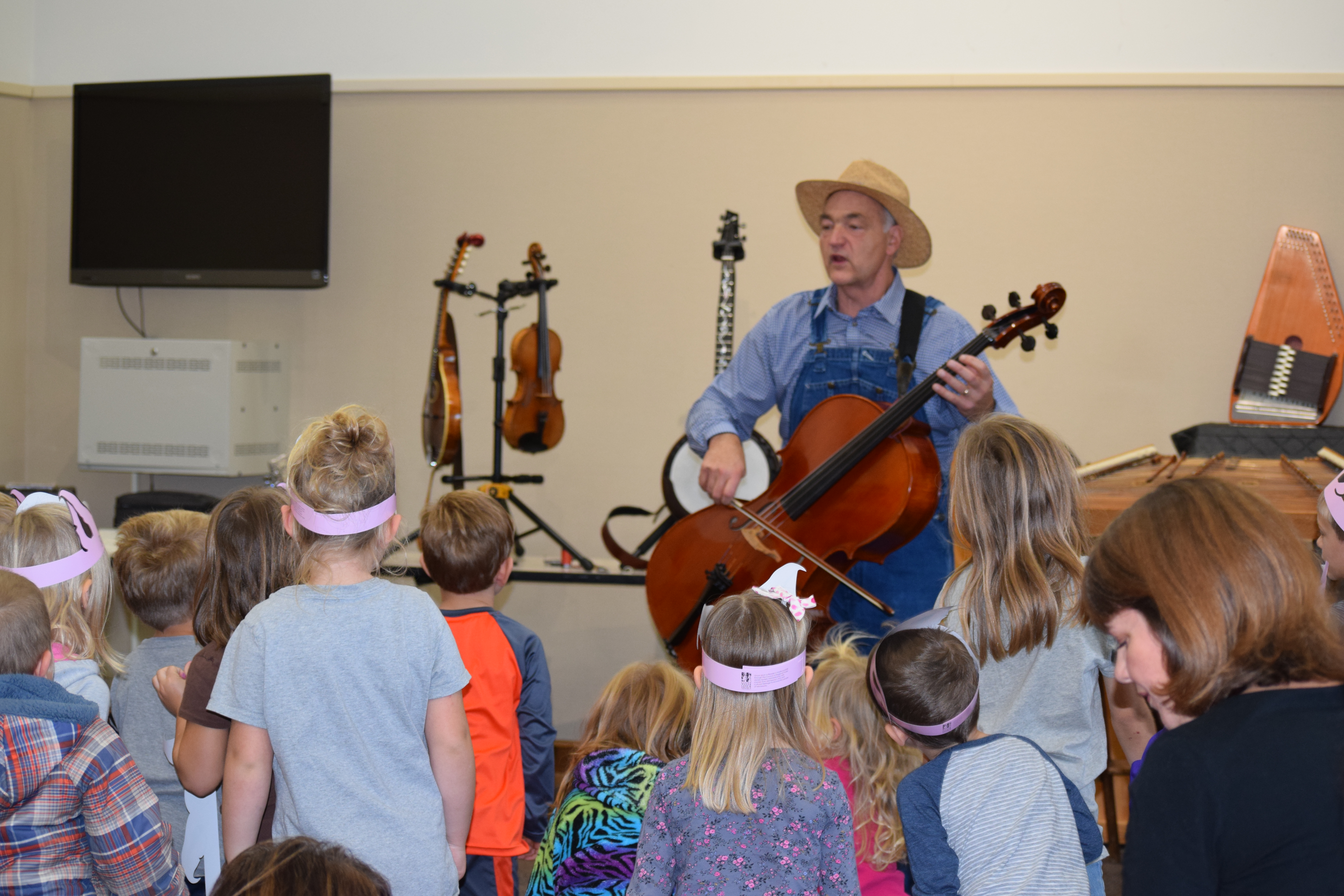 Man In A Stray Hat Playing A Cello With Group Of Children