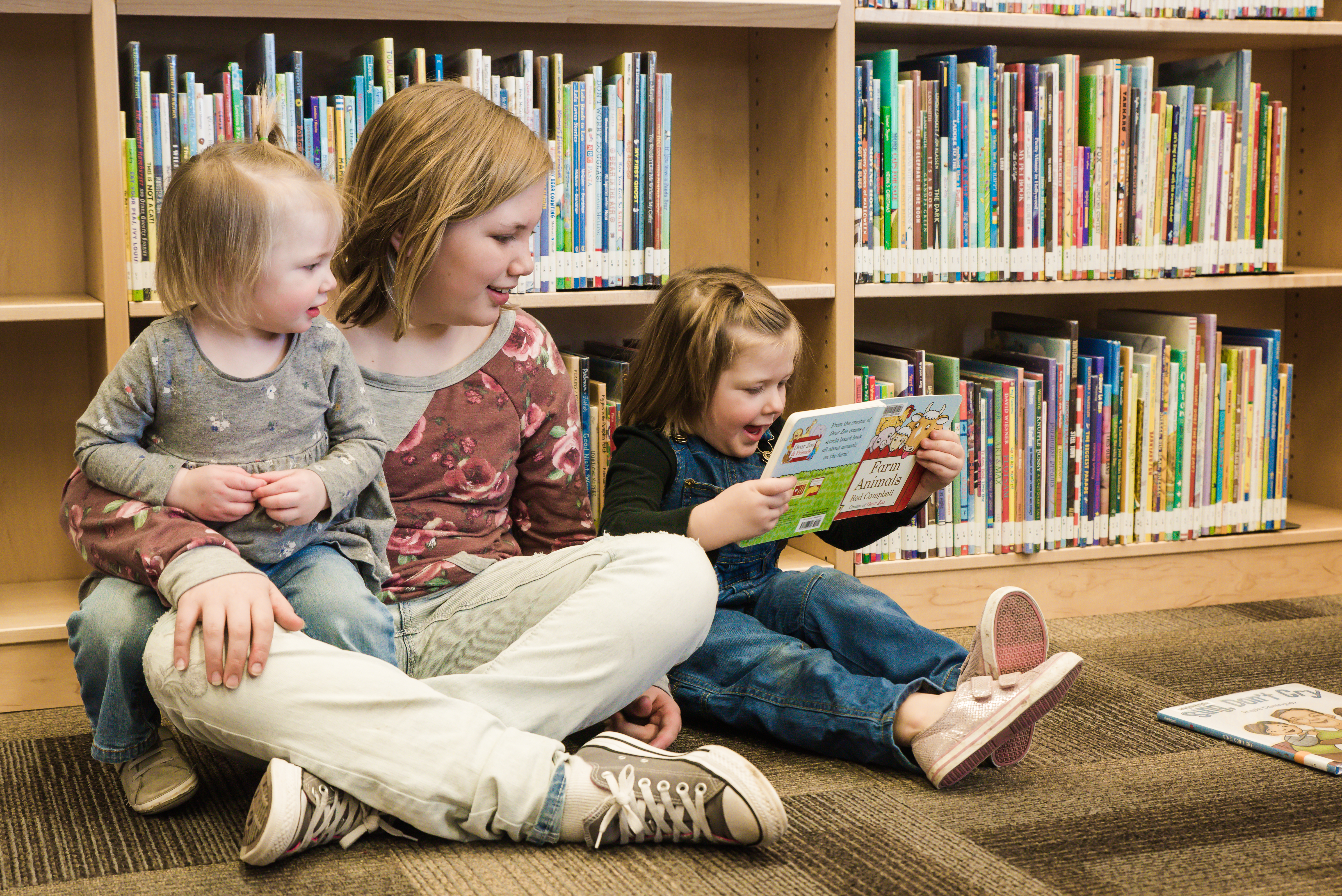 Three Kids Reading A Book About Farm Animals